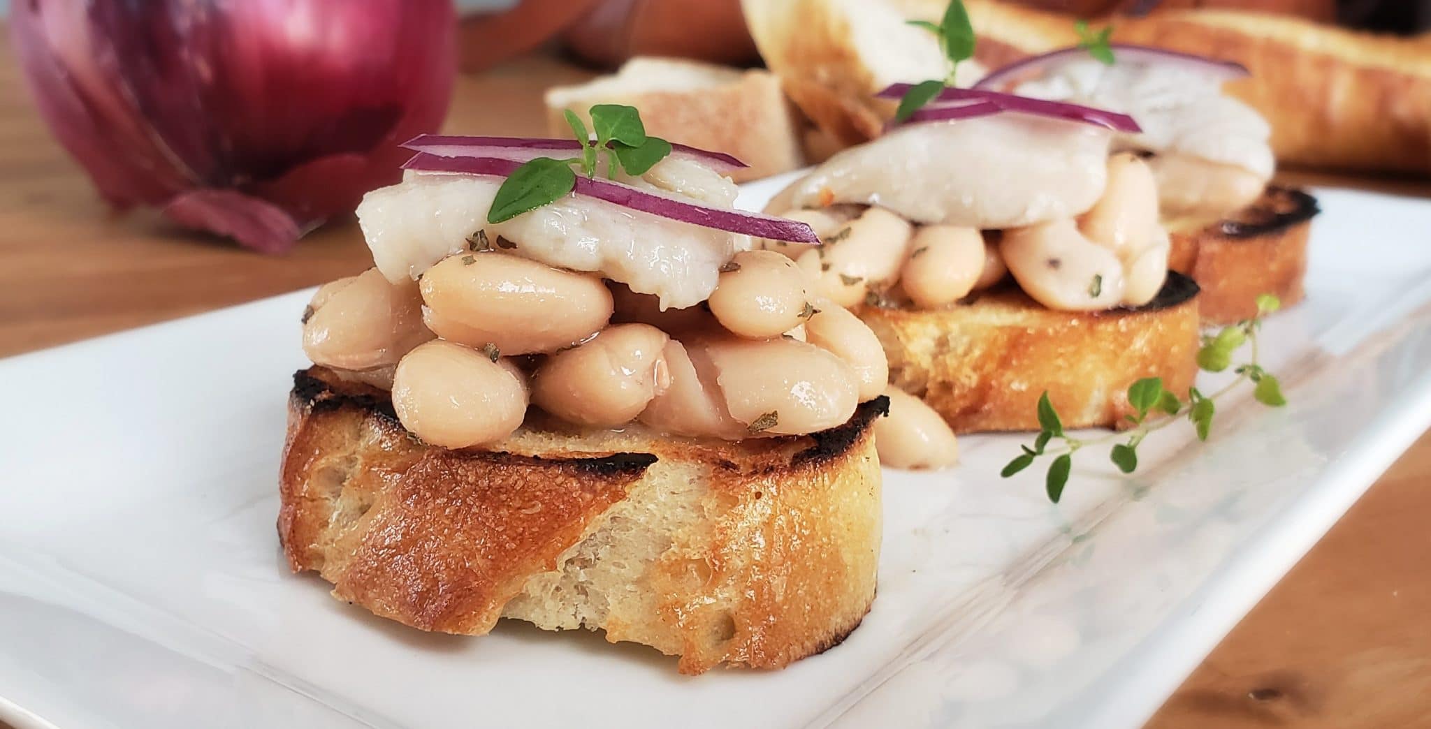 pickled herring with white beans on baguette